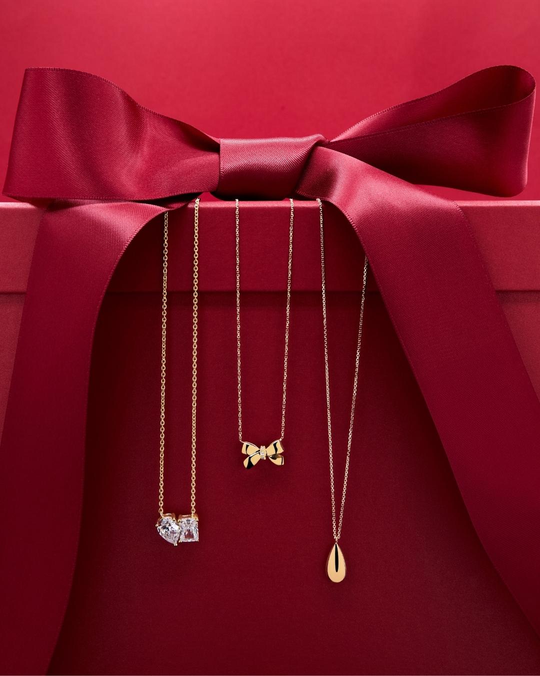 Three 9ct gold necklaces on a red gift box with a bow