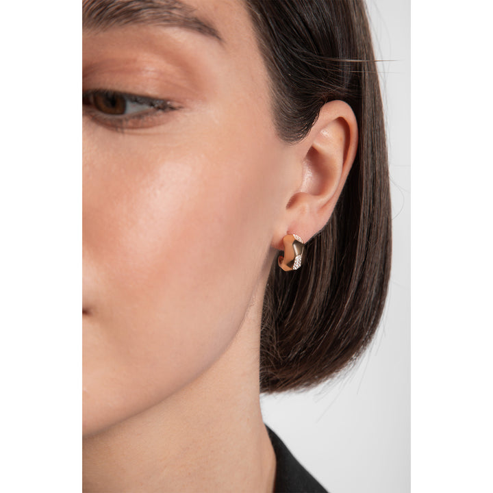 Model wearing chunky gold hoop earrings with cubic zirconia