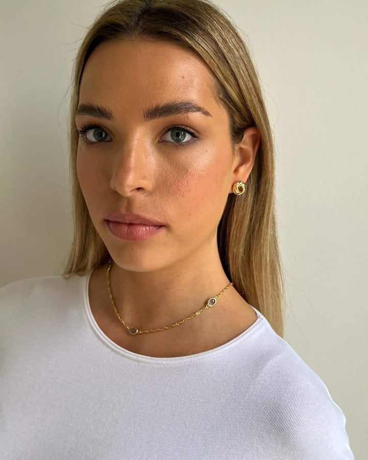 model wearing gold plated lavender oval necklace and gold plated stud earrings