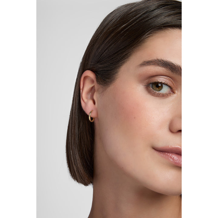 model wearing 9ct gold huggie hoop earrings