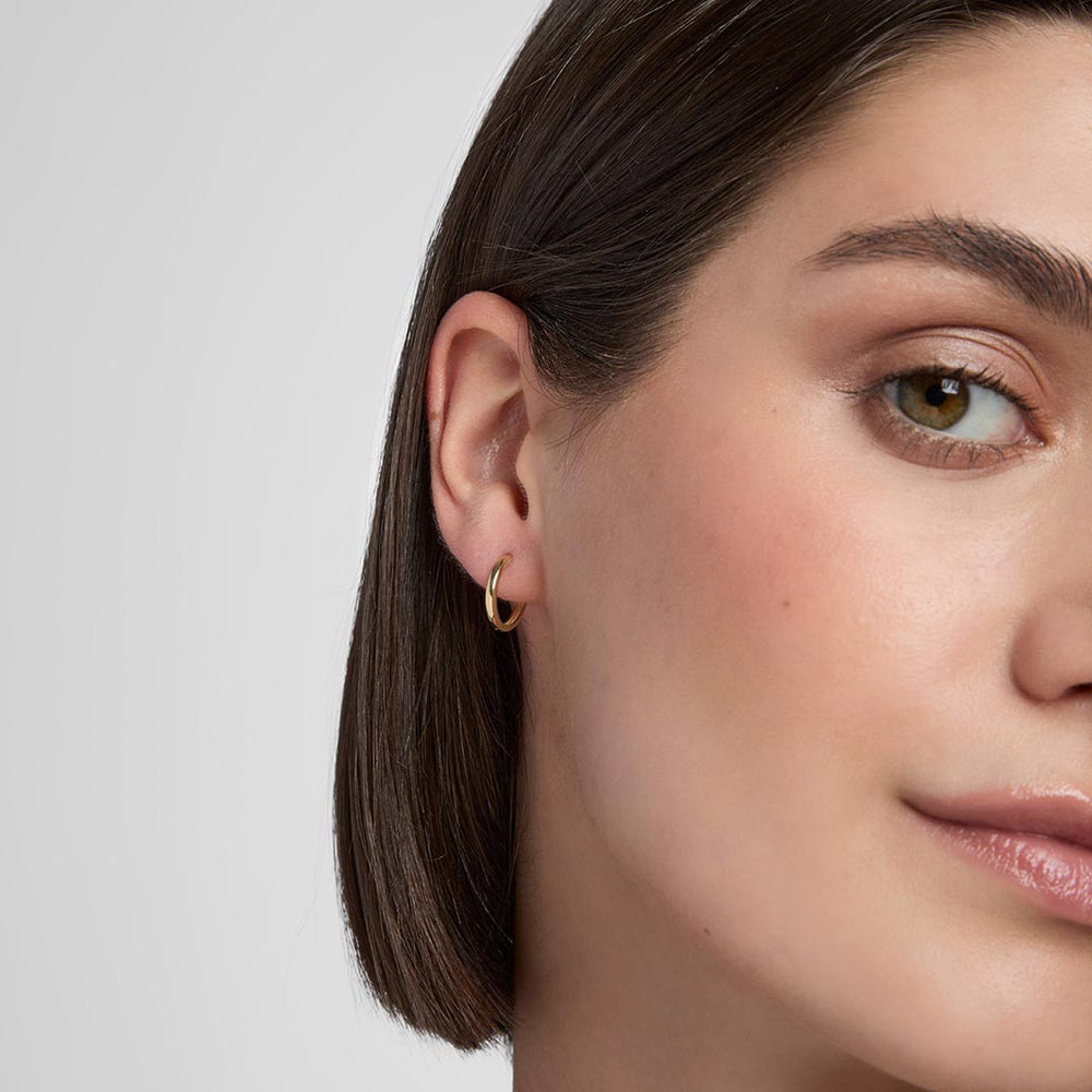 model wearing 9ct gold huggie hoop earrings