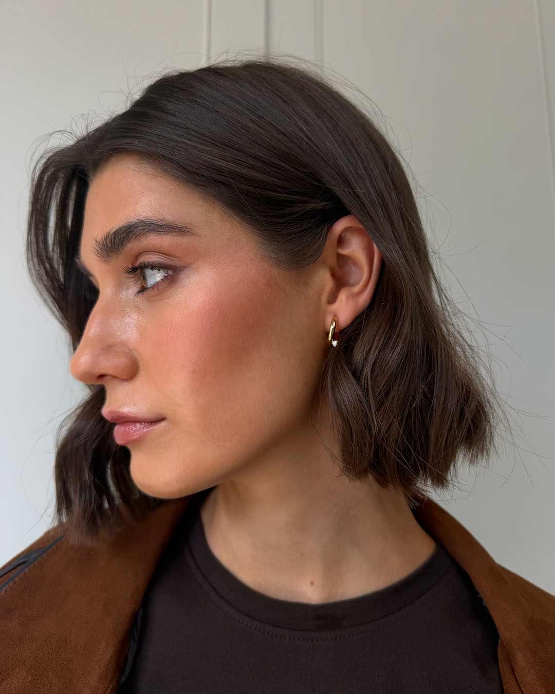 gold plated crossover huggie earrings on model