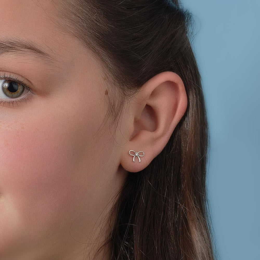 silver bow stud earrings on a model