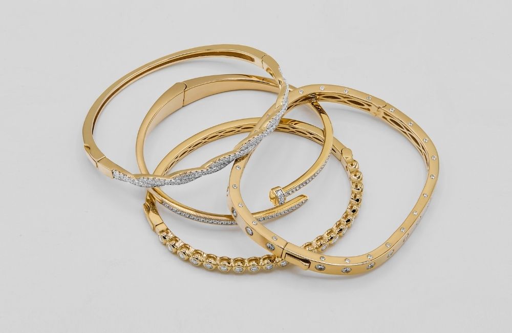 Set of gold bangle bracelets on a light grey background