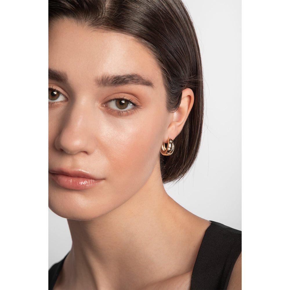 Model wearing chunky gold plated sterling silver hoop earrings with star shaped cubic zirconia