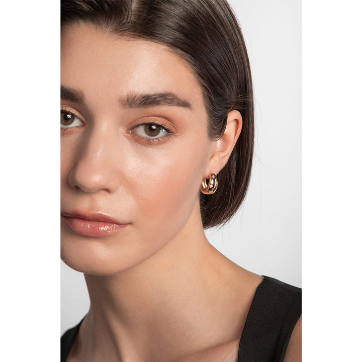 Model wearing chunky gold plated hoop earrings