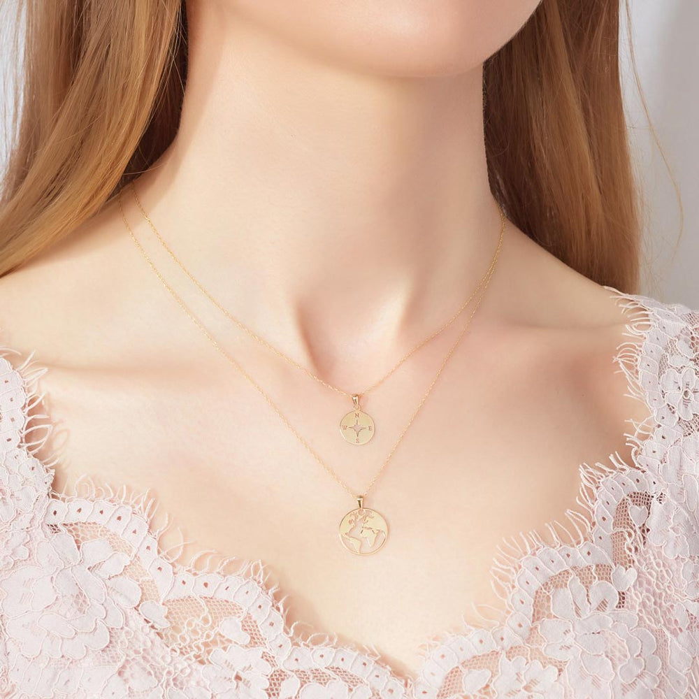 world map necklace and compass necklace in gold on model